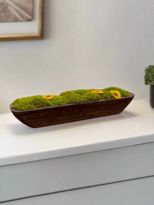 a modern farmhouse style home featuring a rectangular wooden trough arranged with artisanal mood moss, cushion moss, pole moss, and preserved sunflower blooms.