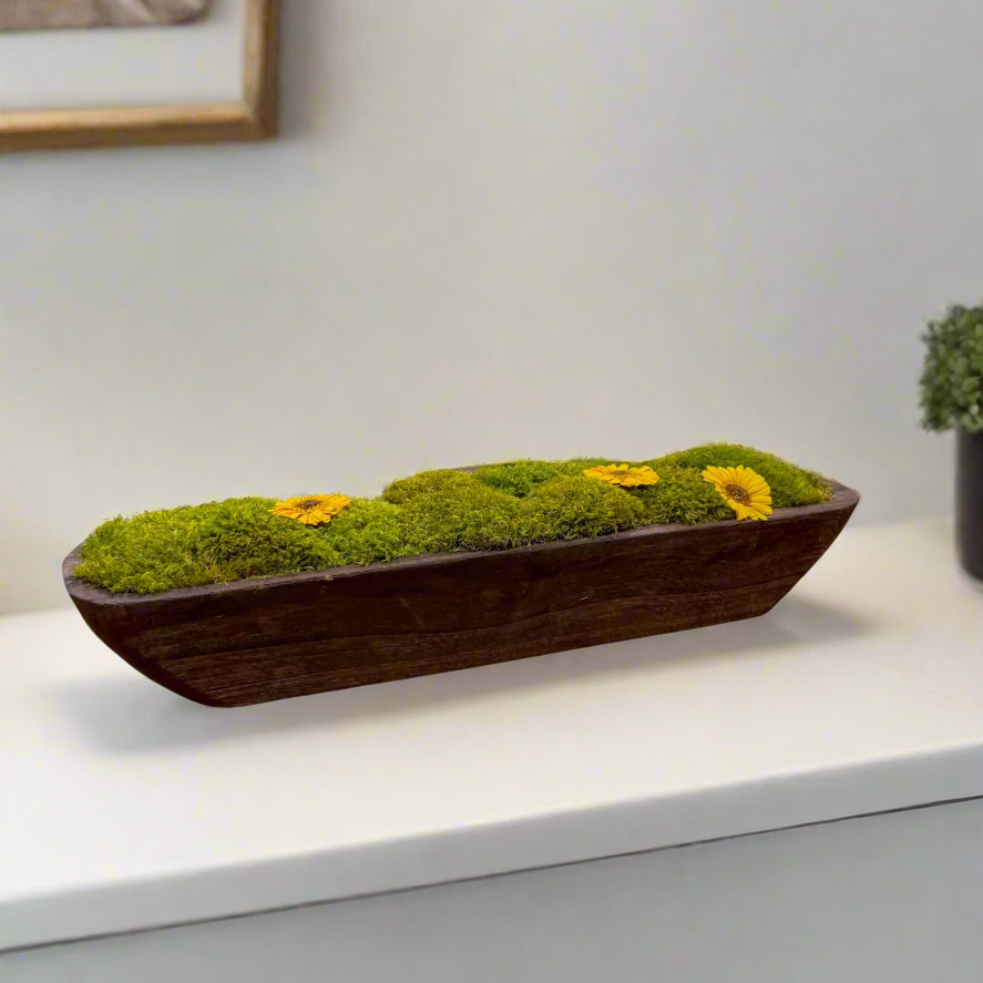 a modern farmhouse style home featuring a rectangular wooden trough arranged with artisanal mood moss, cushion moss, pole moss, and preserved sunflower blooms.