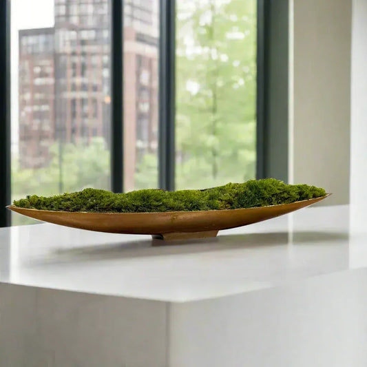 Preserved cushion moss arranged in a metallic gold boat on display in a luxury downtown condo .