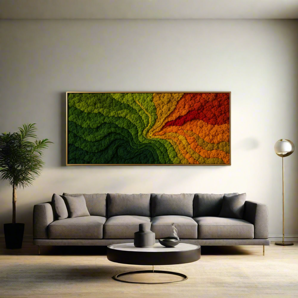Fractal Nature Moss Wall Art displayed above a modern gray sofa in a minimalist living room. The large rectangular moss installation features layered gradients of preserved lichen in vibrant green, yellow, orange, and red hues, forming a swirling, topographic pattern. The artwork is framed in natural wood and illuminated by soft ambient lighting, flanked by a potted indoor plant and a brass floor lamp.
