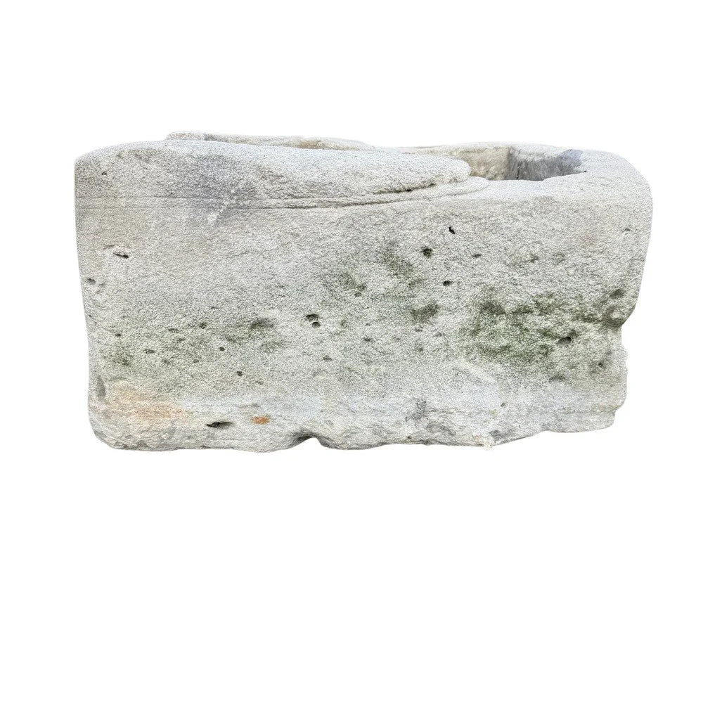 Large stone planter styled on a terrace with sculptural greenery