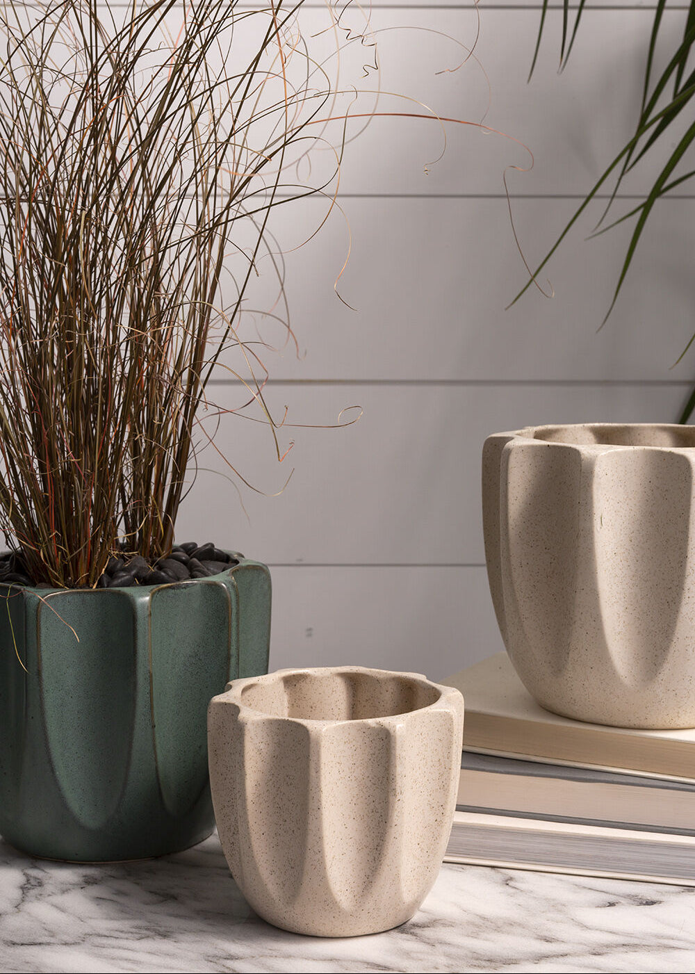 Neutral-toned off-white and green planters styled with an oriential grass on a marble countertop.