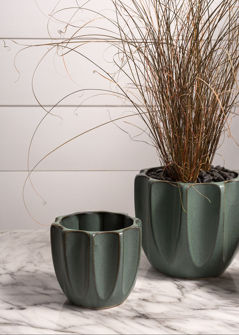 A pair of modern ribbed ceramic pots on a marbled countertop.