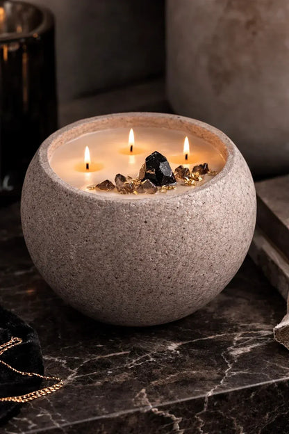 Concrete vessel candle with black obsidian and smoky quartz on a natural stone countertop