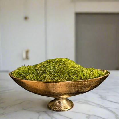 Elegant preserved moss arrangement in a golden pedestal bowl on a marble kitchen countertop of a luxury home in Des Moines, Iowa. 