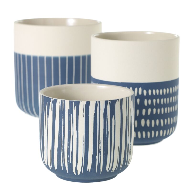 Three ceramic Westview Pots on a pastel blue round table, featuring modern patterns in navy blue and white, set against a vibrant orange and white geometric wall, adding a contemporary touch to indoor decor.