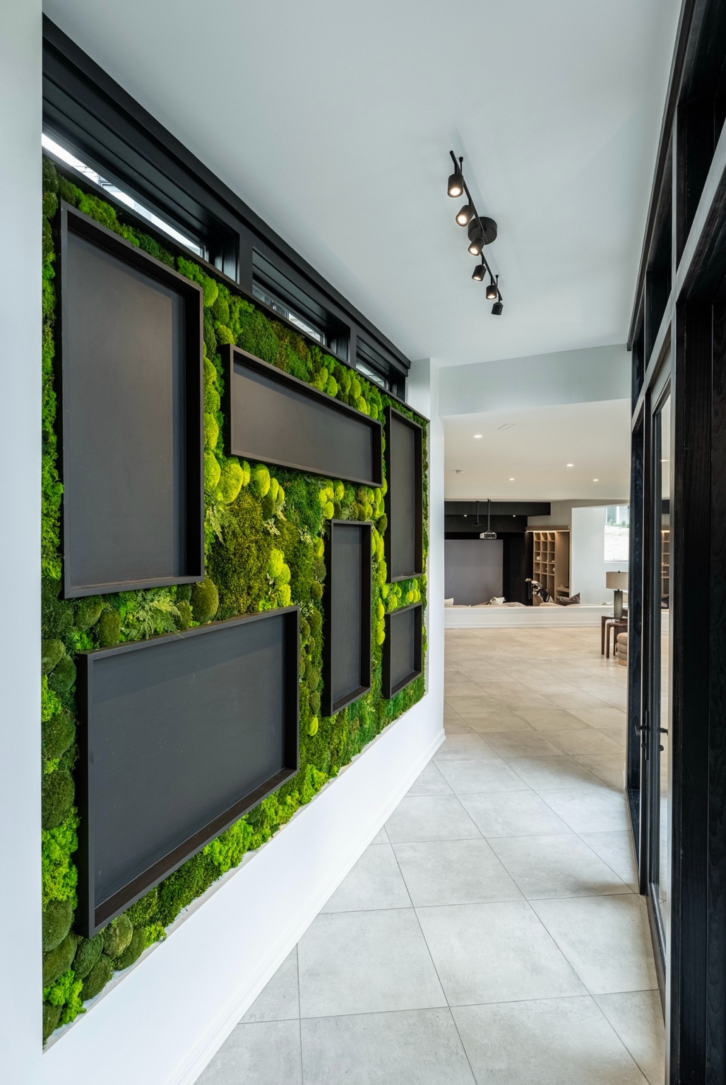 Modern residential hallway featuring a custom preserved moss wall installation with dimensional black display boxes, preserved mood moss, preserved sheet moss, and preserved ferns creating a dramatic biophilic feature wall.